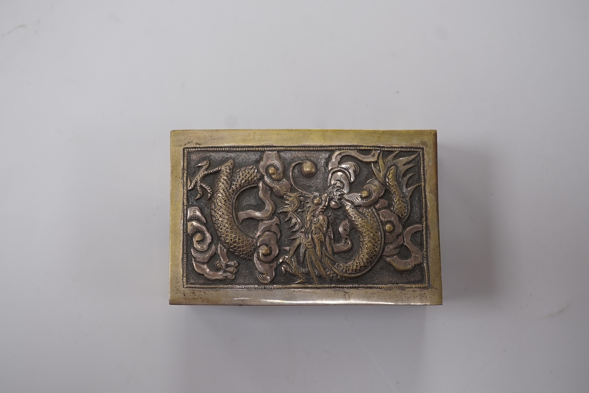 A Chinese Export white metal matchbox holder, with Chinese character mark stamp, embossed and engraved with dragon and prunus, 60mm and a pair of white metal figural menu holders, unmarked.